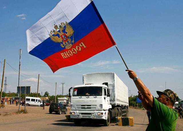 Ein Bewohner der Ostukraine schwenkt z...ung des Konvois eine russische Fahne.  | Foto: SERGEY VENYAVSKY