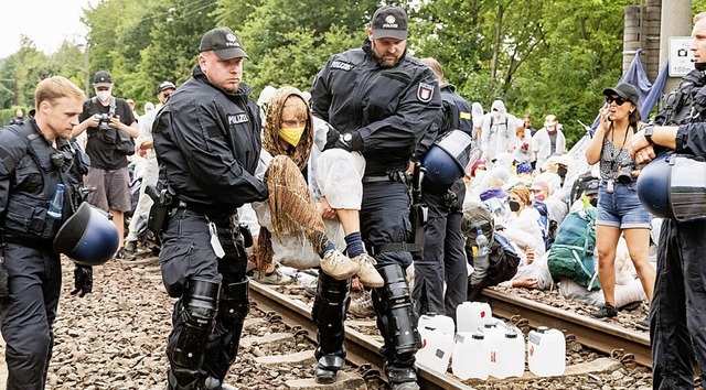 Polizisten trugen die Klimaaktivisten einzeln von den Gleisen.  | Foto: Markus Scholz (dpa)