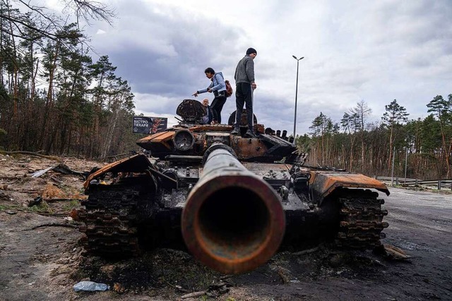 Anwohner stehen auf einem russischen P...enbezirken von Kiew beschdigt wurde.  | Foto: Evgeniy Maloletka (dpa)