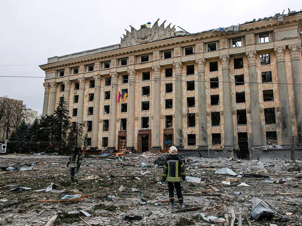 Ein Mitglied des ukrainischen Rettungsdienstes betrachtet das Rathausgebude auf dem zentralen Platz nach russischem Beschuss.