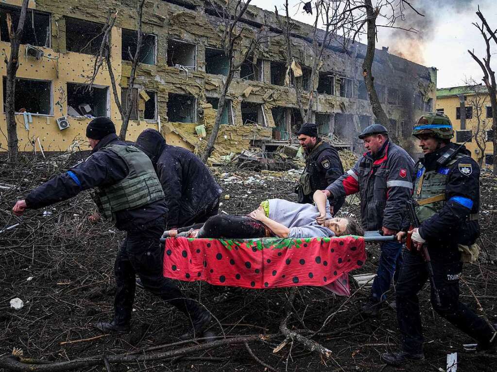 Ukrainische Rettungskrfte und Freiwillige tragen eine verletzte schwangere Frau aus dem Entbindungskrankenhaus, das durch Beschuss beschdigt wurde.  Spter wurde bekannt, dass die Frau ihren Verletzungen erlegen ist.