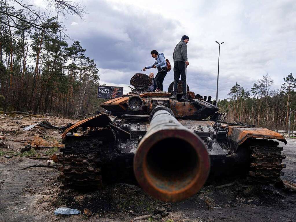 Anwohner stehen auf einem russischen Panzer, der bei Kmpfen zwischen russischen und ukrainischen Streitkrften in einem Auenbezirken von Kiew beschdigt wurde.