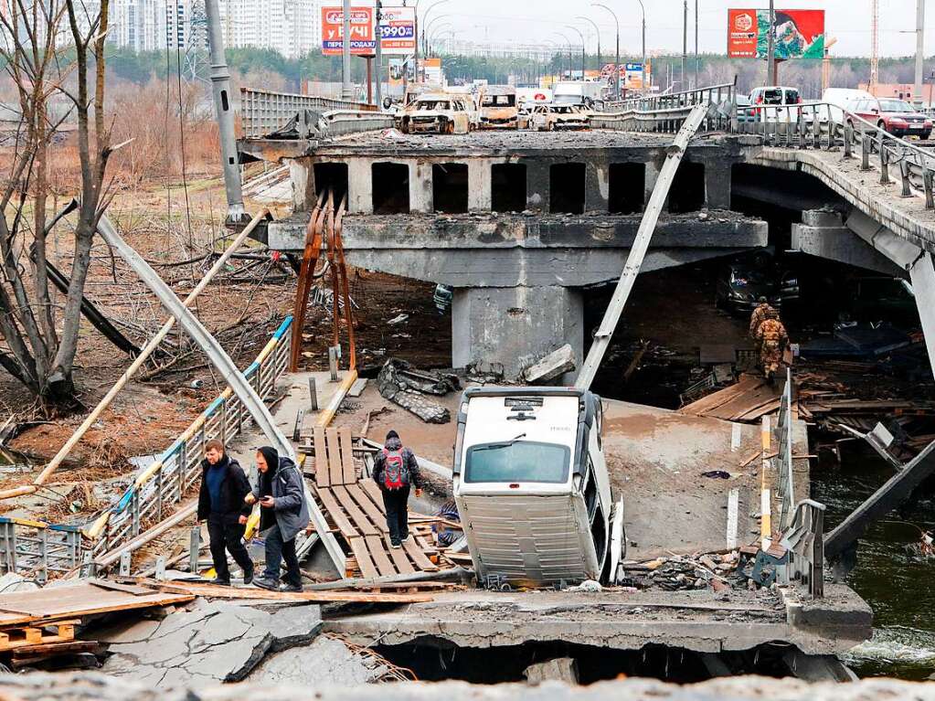 Menschen berqueren eine zerstrte Brcke in Irpin.