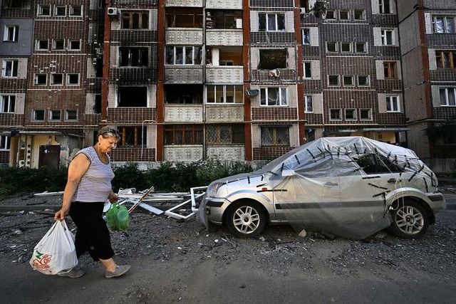 In der Ukraine geht das Sterben jeden ... vor einem zerbombten Haus in Charkiv.  | Foto: GENYA SAVILOV