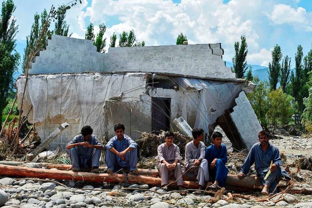 Betroffene der Flut sitzen vor einem zerstrten Haus in Mingora.  | Foto: ABDUL MAJEED (AFP)