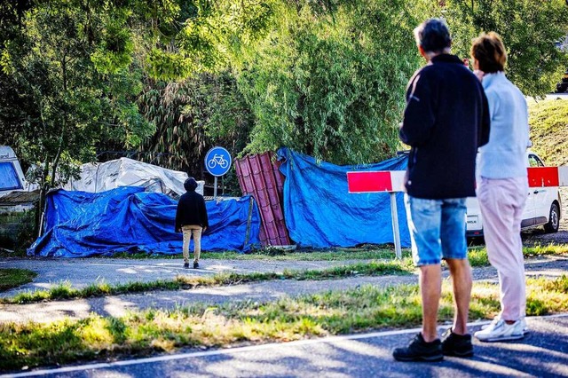 Anwohner stehen an der Unfallstelle, die mit blauen Planen abgedeckt ist.  | Foto: Jeffrey Groeneweg (dpa)