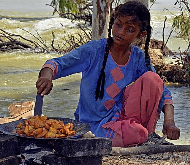 Ein vor der Flut geflchtetes Mdchen kocht Kartoffeln.  | Foto: Shazia Bhatti (dpa)