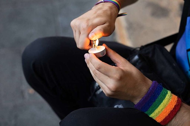 Trauer in Mnster: Ein Mensch mit Rege...en am Handgelenk zndet eine Kerze an.  | Foto: Friso Gentsch (dpa)