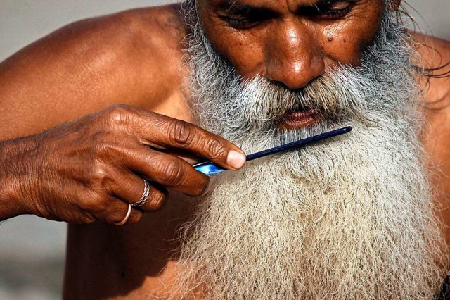 Ein glubiger Hindu pflegt seinen langen Bart.  | Foto: Niranjan Shrestha (dpa)