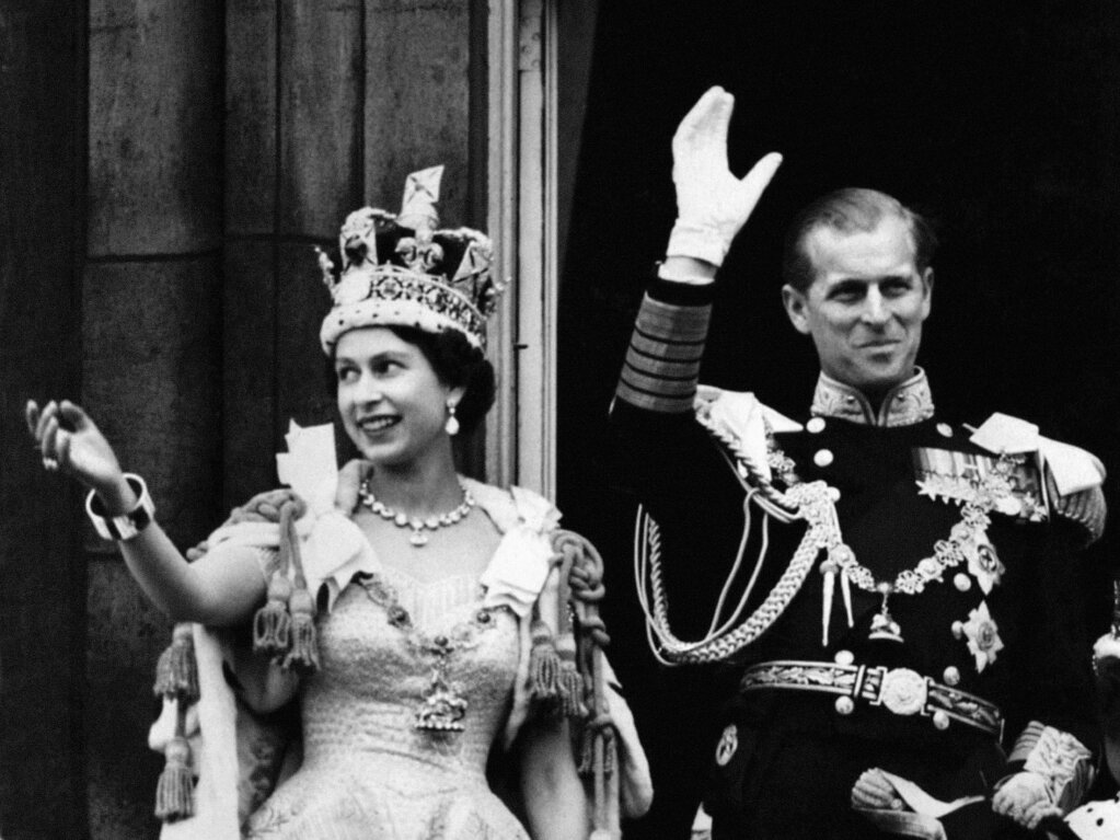 Februar 1953: Knigin Elizabeth II. mit der kaiserlichen Staatskrone und dem Herzog von Edinburgh in der Uniform eines Admirals der Flotte, der vom Balkon des Buckingham Palace nach der Krnung winkt.