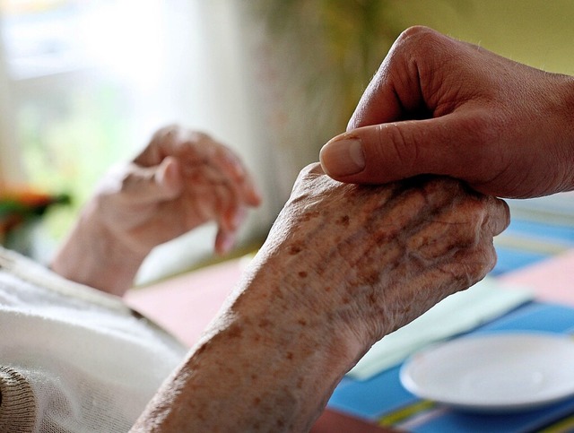 Ein Pfleger hlt die Hand einer Patien...n Pflege vor groen Herausforderungen.  | Foto: Oliver Berg