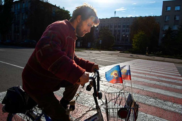 Ein Mann fhrt mit einem Fahrrad, das ... kontrollierten Volksrepublik Luhansk.  | Foto: Uncredited (dpa)