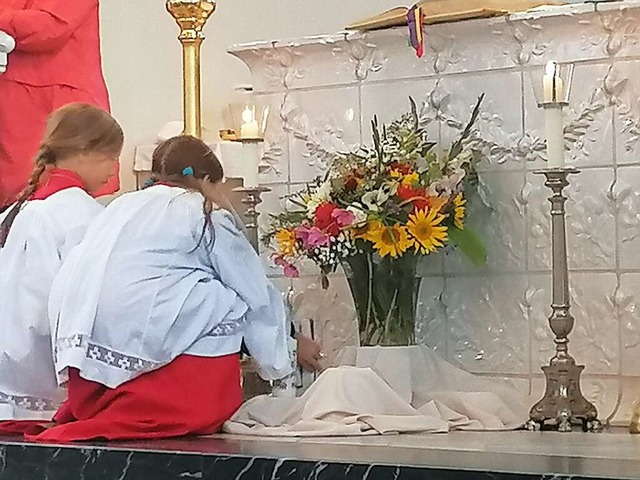 Zwei Ministrantinnen legen Kerze und G...ten Blumenstrau vor dem Altar nieder.  | Foto: Daniel Gramespacher