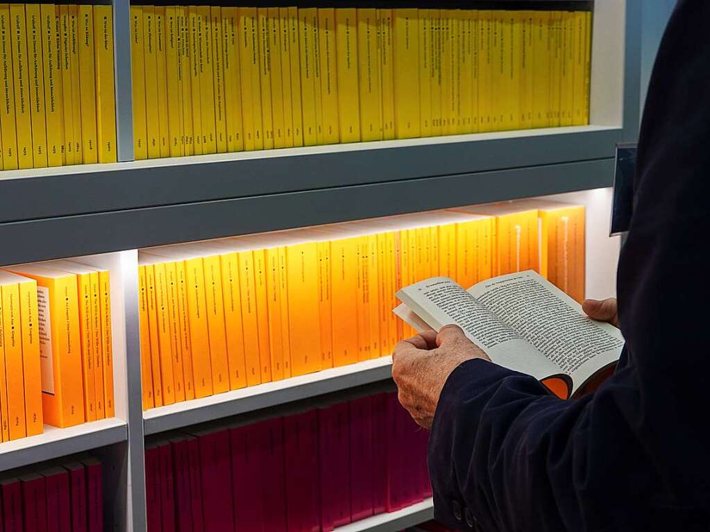 Ein Besucher liest auf der Frankfurter Buchmesse am Stand des Reclam Verlags ein Buch.