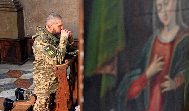 Ein ukrainischer Soldat betet whrend ... fr vier gefallene Kameraden in Lviv.  | Foto: YURIY DYACHYSHYN (AFP)