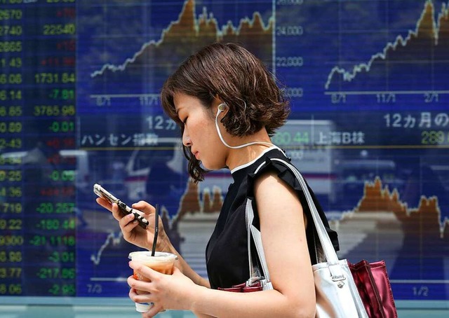 Eine Frau geht in Tokio an einem Monitor, der die Brsenkurse anzeigt, vorbei.  | Foto: Koji Sasahara