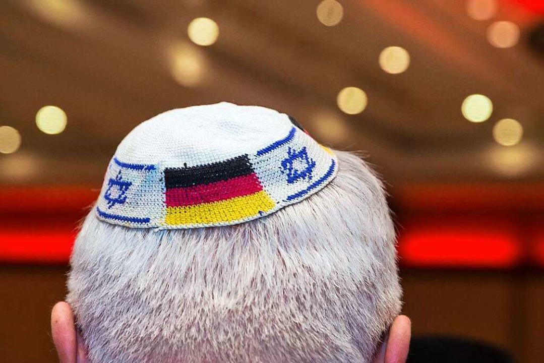 Symbolbild: Ein Mann trägt eine Kippa ...ten israelischen und deutschen Fahnen.  | Foto: Frank Rumpenhorst (dpa)