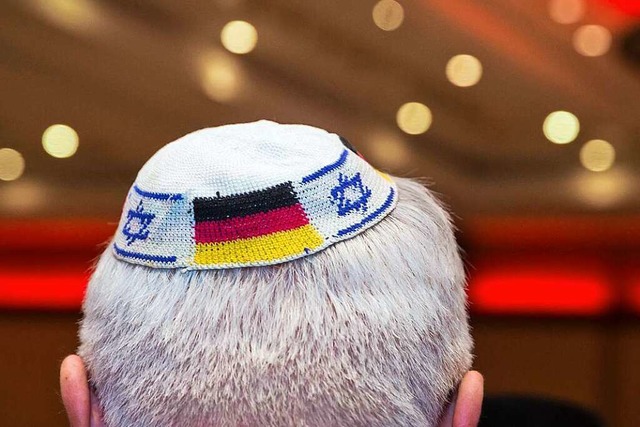 Symbolbild: Ein Mann trgt eine Kippa ...ten israelischen und deutschen Fahnen.  | Foto: Frank Rumpenhorst (dpa)