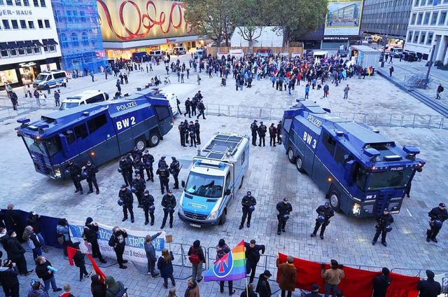 Polizisten stehen mit Wasserwerfern am...dgebung (im Hintergrund) protestieren.  | Foto: Andreas Rosar (dpa)
