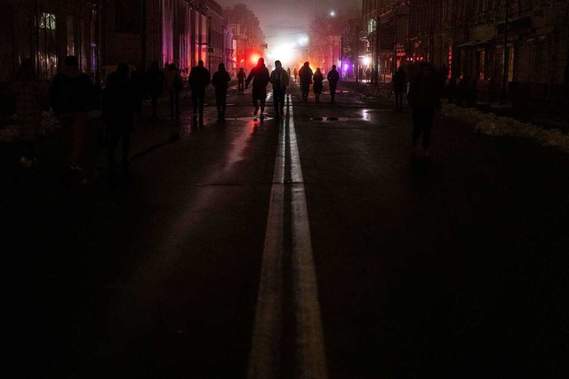 Menschen spazieren am Donnerstag durch...enangriff am Tag zuvor ohne Strom ist.  | Foto: Evgeniy Maloletka (dpa)