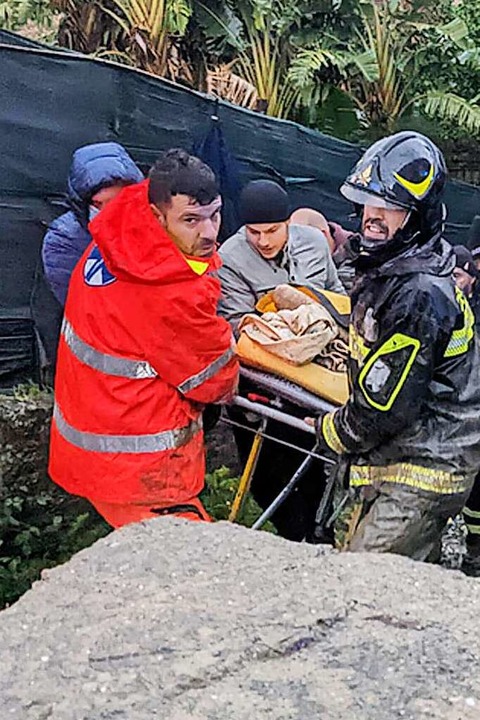 Italienische Rettungskräfte tragen einen Mann aus seinem Haus.  | Foto: - (AFP)