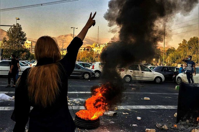 Eine Frau steht whrend einer Demonstr...oreifen und zeigt das Victory-Zeichen.  | Foto: Uncredited (dpa)