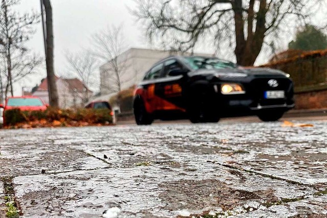 Ein Auto fhrt an einem mit Eis bedeckten Gehsteig vorbei.  | Foto: Mark Alexander (dpa)