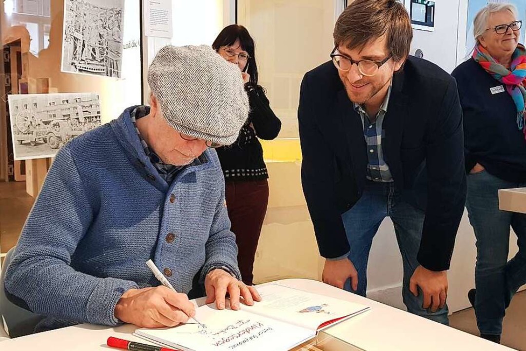 Peter Gaymann beim Signieren eines Buches mit BZ-Moderator Bastian Bernhardt  | Foto: Christian Kramberg