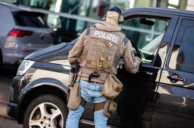 : Ein Polizist steht an einem Einsatzfahrzeug und spricht mit einem Kollegen.  | Foto: Christoph Schmidt (dpa)