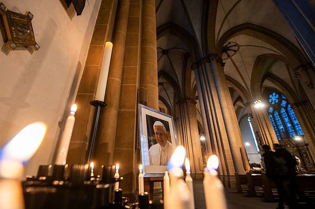 Ein Portrtbild des emeritierten Papst...ter Andachtskerzen im Paderborner Dom.  | Foto: Lino Mirgeler (dpa)