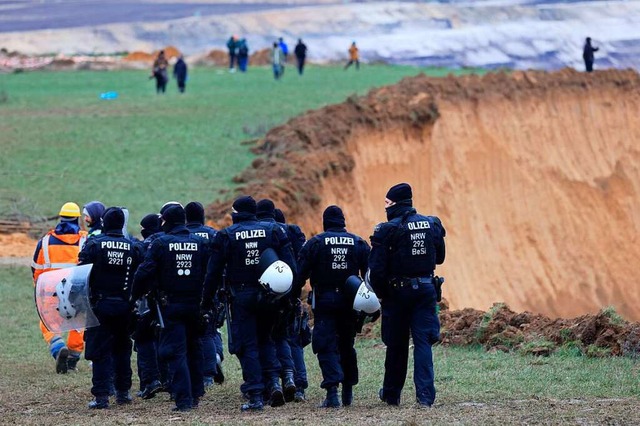 Polizisten gehen am Rand des Tagebaus.  | Foto: Oliver Berg (dpa)