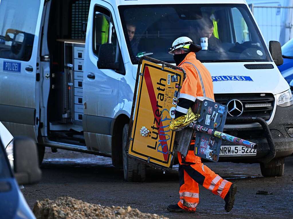 Ein RWE Mitarbeiter trgt das abgesgte Ortsschild des Dorfes Ltzerath fort.