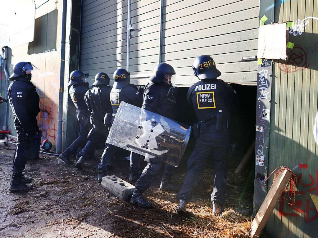 Polizisten rcken in den von Klimaaktivisten besetzten Braunkohleort Ltzerath vor und ffnen das Tor einer Halle auf der Suche nach Aktivisten.