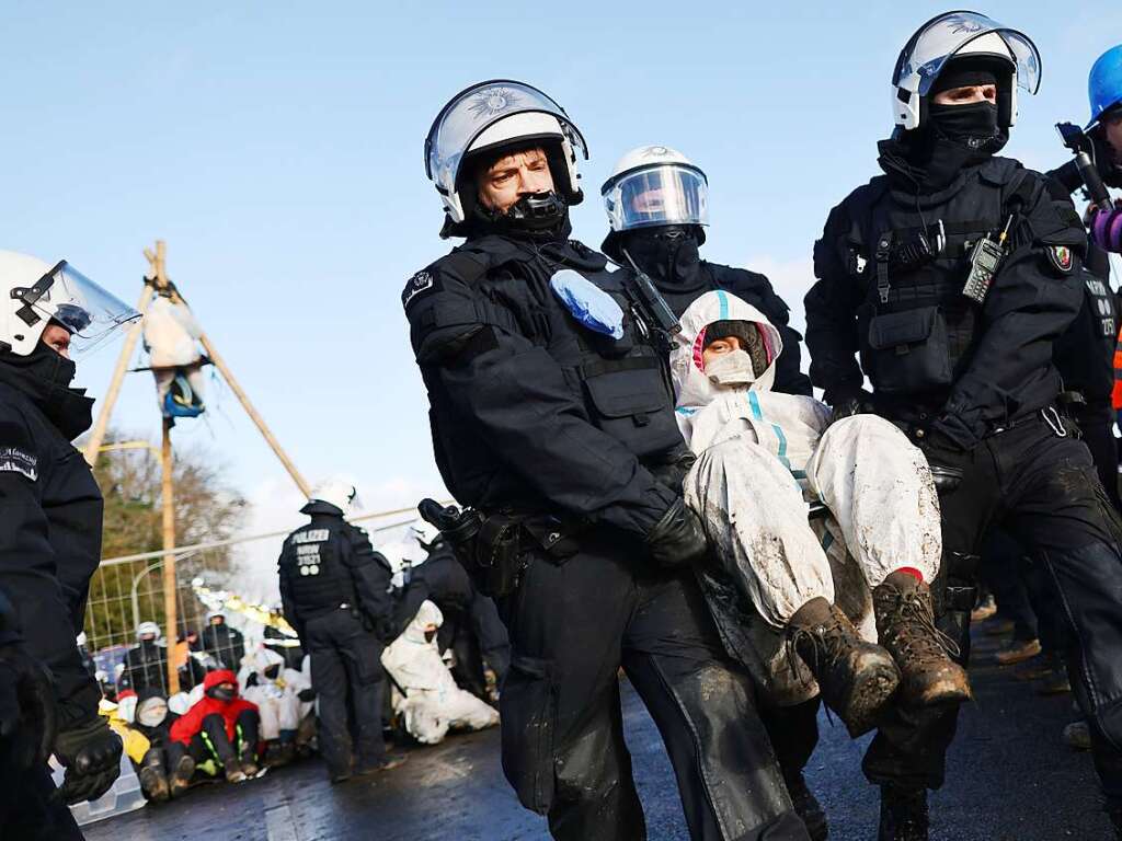 Polizisten tragen einen Klimaaktivisten vom besetzten Braunkohleort Ltzerath weg.