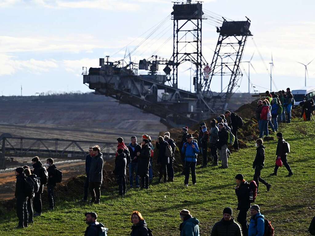 Klimaschutzaktivisten stehen vor einem Schaufelradbagger am Rand des Tagebaus.