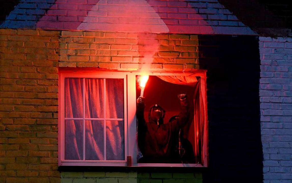 Ein Klimaaktivist hält eine Fackel aus...r eines besetzten Hauses in Lütezrath.  | Foto: INA FASSBENDER (AFP)
