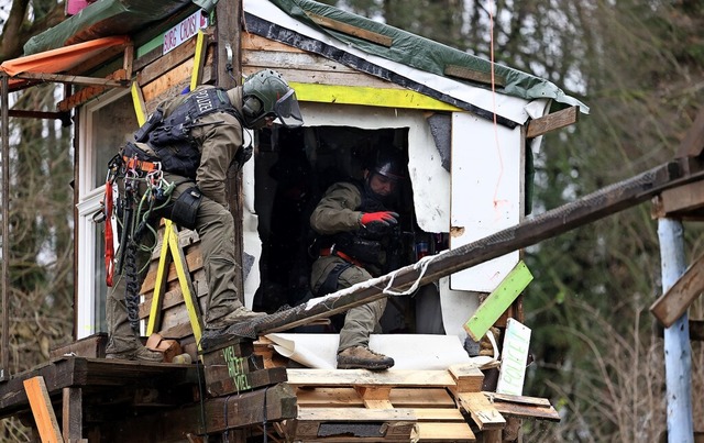 Polizisten durchsuchen ein von Klimaak...n aufgegebenes Holzhaus bei Ltzerath.  | Foto: Rolf Vennenbernd (dpa)