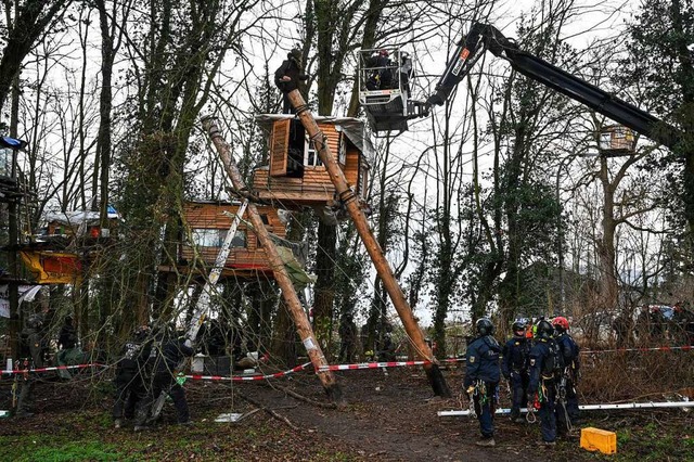 Polizisten sprechen mit einem Aktivisten in Ltzerath.  | Foto: Henning Kaiser (dpa)