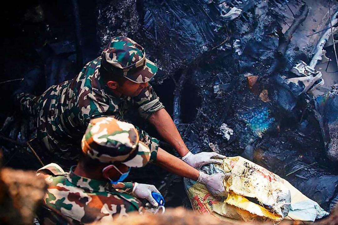 Rettungskräfte inspizieren den Unfallort.  | Foto: YUNISH GURUNG (AFP)