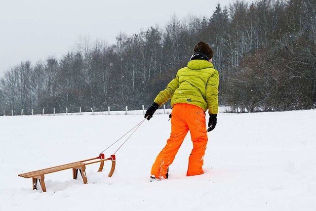 Ein Kind zieht seinen Schlitten im Schnee einen Abhang hoch.  | Foto: Friso Gentsch (dpa)
