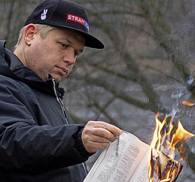 Der rechtsextreme Politiker Rasmus Paludan verbrennt  in Stockholm einen Koran.  | Foto: Joel Lindhe (dpa)