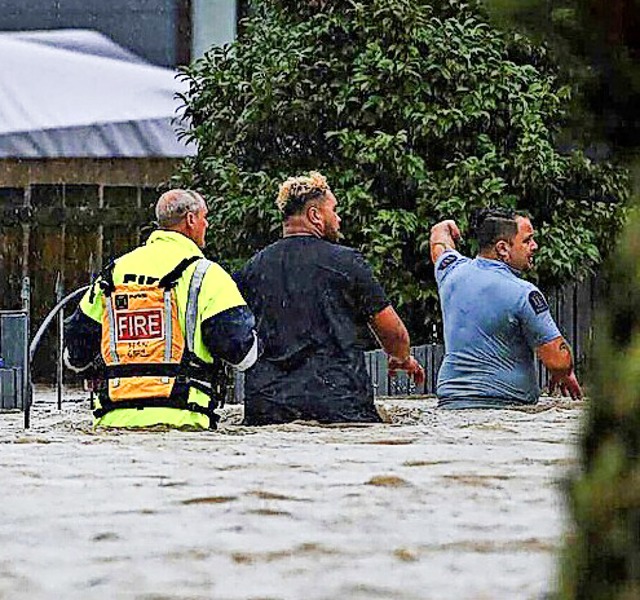Rettungskrfte und ein Mann waten durch das Hochwasser.  | Foto: Hayden Woodward (dpa)