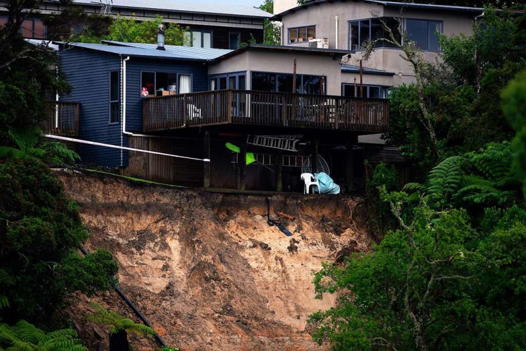 Ein durch Hochwasser verursachter Erdrutsch untergräbt ein Haus.  | Foto: Hadyen Woodward (dpa)
