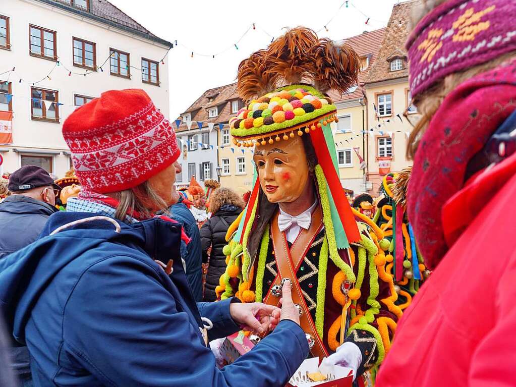 Ein Schmberger Fransennarr verteilt Pralinen an Zuschauer.