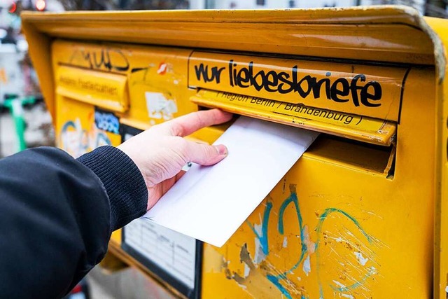 Ein Mann wirft einen Brief in einen Briefkasten.  | Foto: Christophe Gateau (dpa)