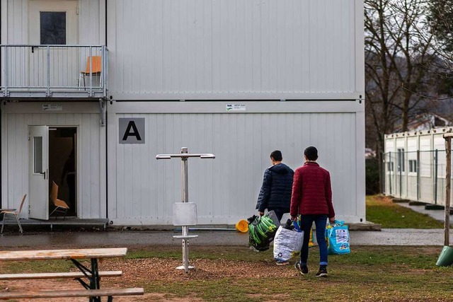 Zwei Migranten ziehen mit Plastiktten...ontainer einer Unterkunft in Sdbaden.  | Foto: Philipp von Ditfurth (dpa)
