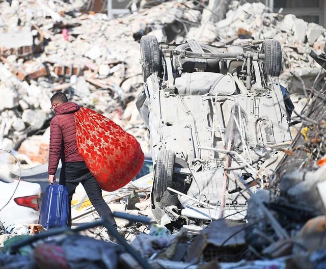 Trkei, Antakya: Ein Mann trgt seine Habseligkeiten ber Erdbebentrmmern.  | Foto: Shadati (dpa)