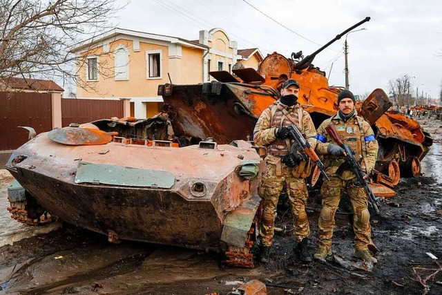 In der ukrainischen Stadt Butscha steh...or einem zerstrten russischen Panzer.  | Foto: IMAGO/Daniel Ceng Shou-Yi