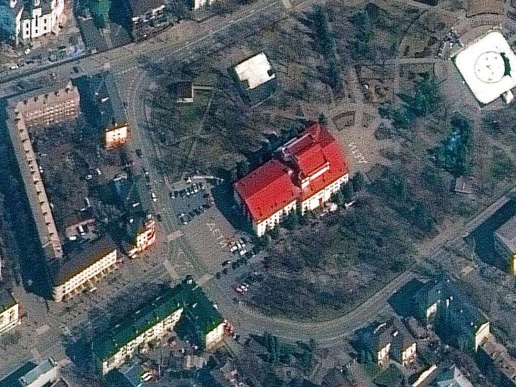 Ein Satellitenbild zeigt das Theater von Mariupol. Die Russische Armee ignoriert spter die Warnung „Kinder“ auf dem Pflaster und zerstrt das Gebude. Hunderte sterben.