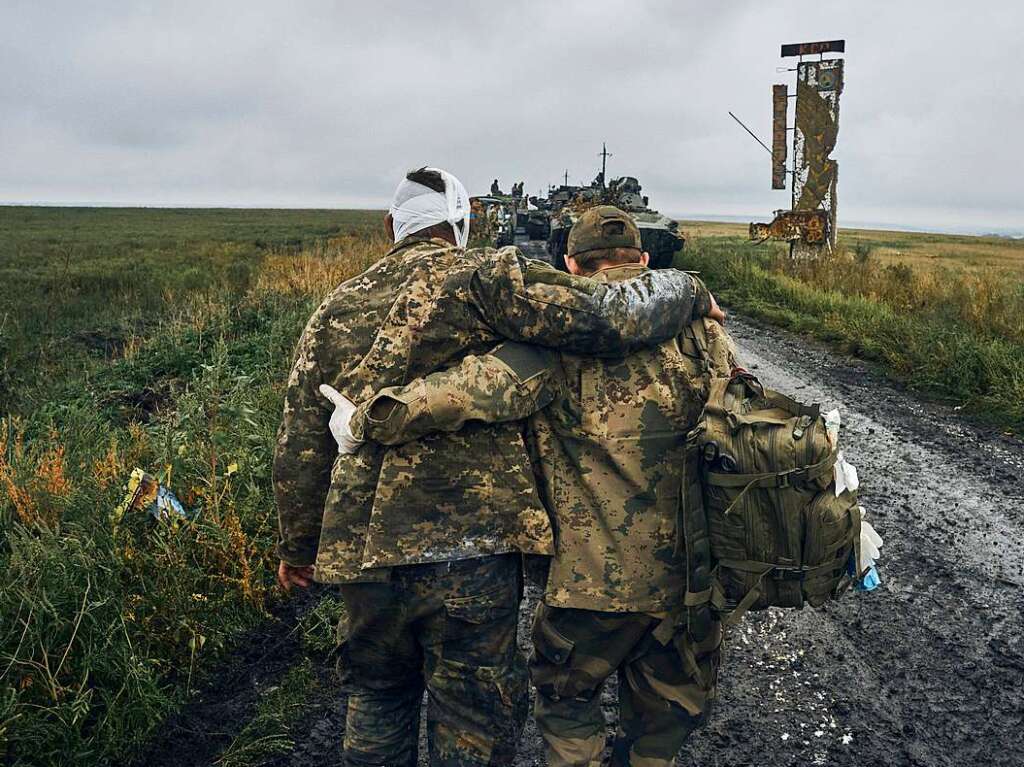 Ein ukrainischer Soldat hilft einem verwundeten Kameraden auf der Strae in dem befreiten Gebiet in der Region Charkiw.